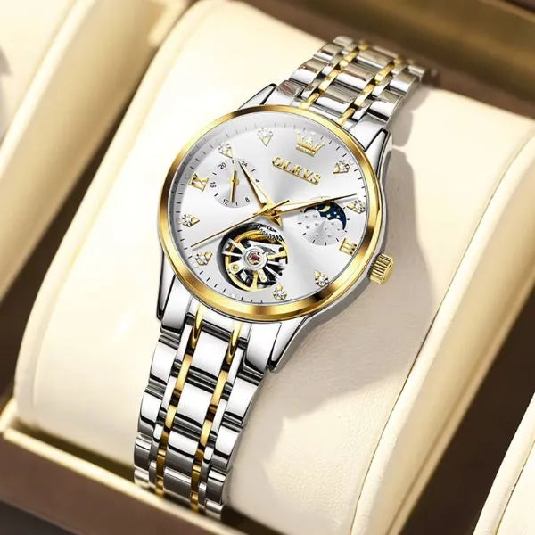 Montre femme OLEVS Charlotte à cadran blanc et détails dorés posée sur un coussin