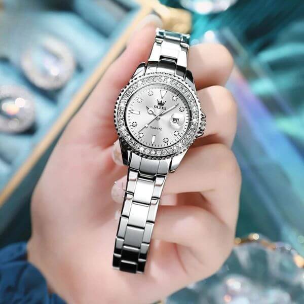 Montre Olevs Apolline argentée à cadran blanc tenue à la main
